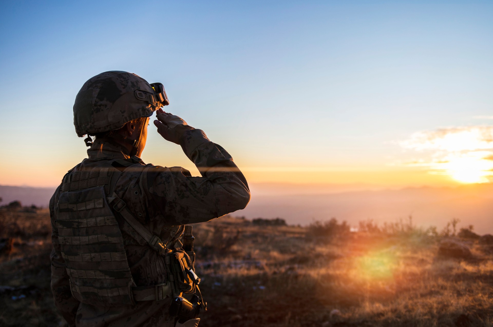 Female Army Solider Saluting against sunset sky